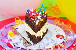 A piece of chocolate cake with colorful sprinkles and candy decorations for a party