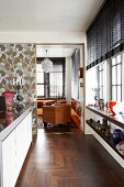 View through patterned sliding door into tasteful office with pretty pendant lamp and brown leather armchairs