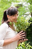 Frau riecht an einer Pfefferminzpflanze im Garten