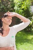 Woman in the hot summer sun with a water bottle in the garden