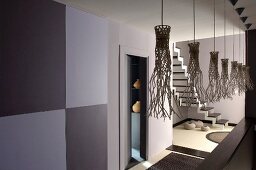 Künstlerisch gestaltete Schirme von Hängeleuchten in grau getönten Gangbereich und Blick ins Treppenhaus