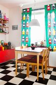 Esstisch in Küche mit Schachbrettmusterboden & bunten Fenstervorhängen