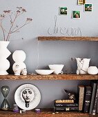 White ceramics, collection of ornaments and books on floating shelves made from rustic wooden boards