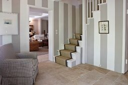 Walls with wide stripes and stone flags in classic foyer with foot of stairs