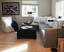 Corner sofa, ottoman and loose-covered armchair in front of framed Union Flag