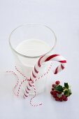 Ein Glas Milch mit Zuckerstange, daneben Ilexbeeren