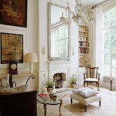 Seating area in front of fireplace with antique furniture and paintings; view into garden