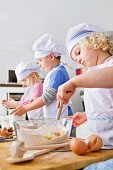 Germany, Girls and boy making dough in kitchen