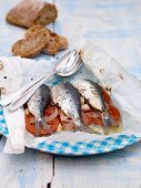 Sardines with tomatoes, onions and garlic cooked in parchment paper