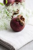 Mangosteen on a linen tablecloth with white flowers in the background