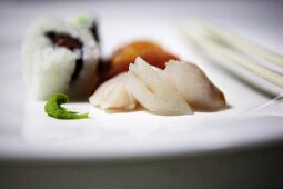 Uramaki and nigiri sushi; sashimi and wasabi paste to the front