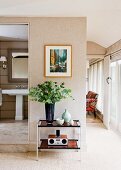 Bouquet on console table below modern painting on wall with natural fibre wallpaper next to open bathroom door