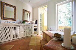 Grossräumiges Bad mit Waschtisch und Unterschränken auf Terrakottaboden gegenüber Badewanne am Fenster