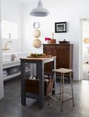 Original sink unit with two china basins and wall-mounted tap fitting in converted kitchen with vintage cupboard and simple work bench below pendant lamp