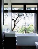 Contemporary black and white bathroom with view of landscape through open sliding glass wall