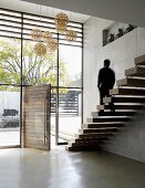 Minimalist staircase with floating wooden treads in foyer with glass facade and open front door