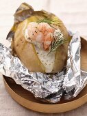 Foil-wrapped baked potato with prawns and sour cream