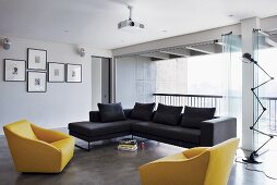 Bright, modern living room with yellow and blue sofa and armchairs; open folding glass doors providing access to balcony