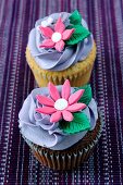 A chocolate cupcake and a lemon cupcake topped with purple icing