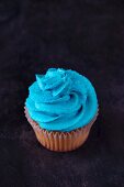 A vanilla cupcake topped with blue buttercream icing