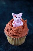 A cupcake topped with a piglet in mud