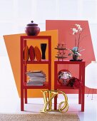 Magazines, cushions and various ornaments in stacked, red shelving modules in front of brightly coloured partitions