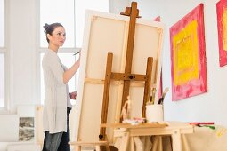 Woman painting picture on easel in artist's studio