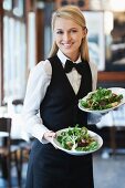 A waitress serving plates of salad in a pub