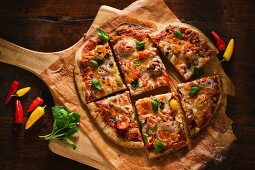 A Veggie Pizza with Fresh Basil Sliced on a Pizza Board; From Above