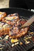 Mariniertes Lammfleisch auf dem Holzkohlengrill wenden