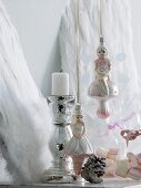 Angel Christmas tree baubles next to chrome candlestick in front of decorative angels' wings leaning on wall