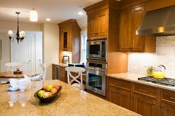 Spacious country-house kitchen with solid wood cupboard doors and large stone worksurface in foreground