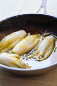 Chicory with orange sauce in a frying pan