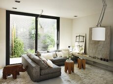 Corner sofa with small tables and Flokati rug in front of sliding glass door with a view of a plant wall, modern art and elephant sculpture