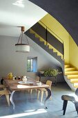 Designertisch mit Holzstühlen vor anthrazitfarbener Wohnraumtreppe