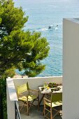 Director's chairs with green canvas seats on terrace of house with view of ocean and boat passing by