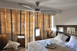 Modern bedroom with double bed below ceiling fan next to windows with closed Roman blinds