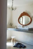 Antique oval mirror above narrow concrete washstand, delicate stool and crystal chandelier in Provençal bathroom