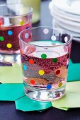 A drinking glass decorated with colourful dots