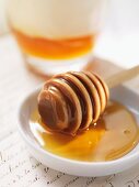 Honig mit Honiglöffel vor Milchglas