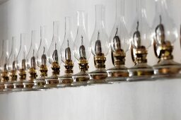 Row of identical oil lamps against white wall