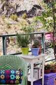 Rattan armchair and potted plants on table on loft-apartment terrace opposite rock face