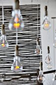 Simple, hanging bare bulbs in front of a see through, wicker, room divider