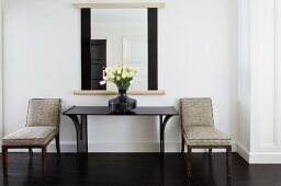 Gepolsterte Stühle neben Wandtisch und Spiegel in klassischem Ambiente