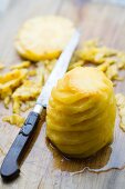 A peeled pineapple cut into a spiral shape with a knife