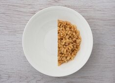 A halved portion of cereal in a white bowl (view from above)
