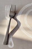 Fork on pale grey paper place mat with fork and plate motif