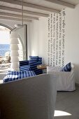 Various armchairs with loose covers and designer standard lamp in Mediterranean interior with sea view