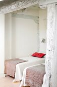 Elegante Einzelbetten in Nische eines rustikalen Schlafzimmers mit geweisselter Holzkonstruktion