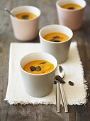 Several portions of pumpkin soup topped with pumpkin seeds